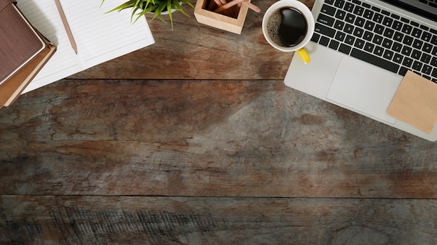 Top view of laptop, notebook, pencil and coffee cup on wood desk 