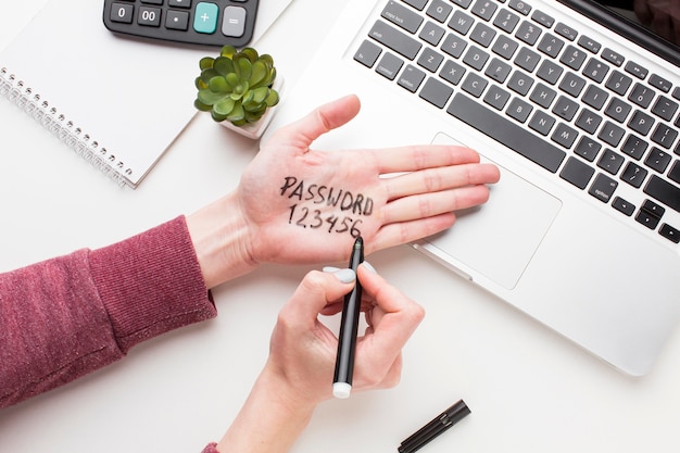 Photo top view of laptop with hand with password written on it