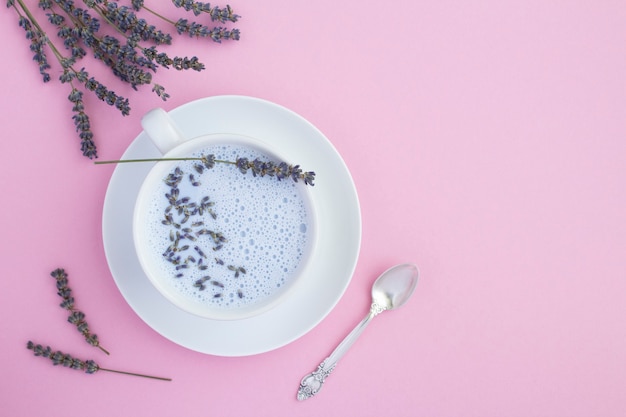 Top view of lavender moon milk in the white cup on the pink surface.