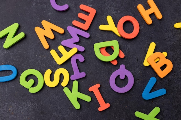 黒い背景に散らばった英語アルファベットの文字のトップビュー