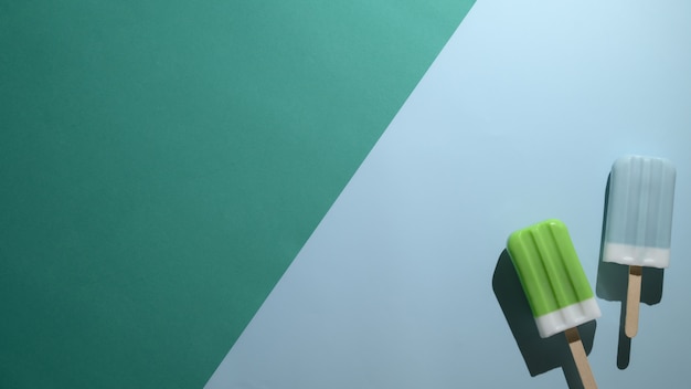 Top view of lime and blue raspberry flavour popsicles on flat lay green and  blue background