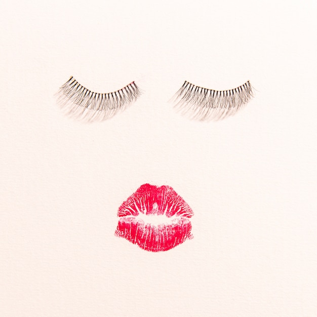 Top view of lips and eyelashes on plain background