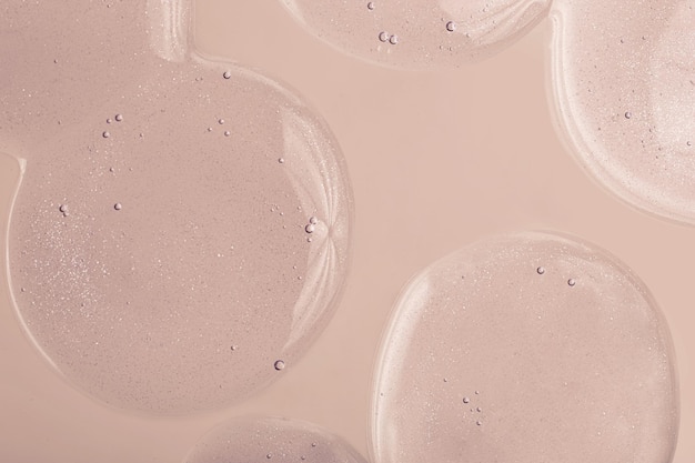 Photo top view of liquid cosmetics gel with bubbly structure on pastel beige background