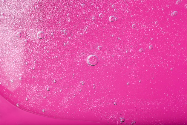 분홍색 배경에 거품 구조가 있는 액체 화장품 젤의 상단 보기
