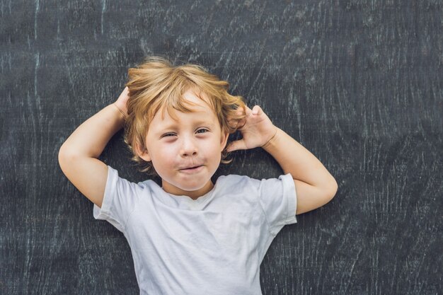 古い木製のテキストと記号のためのスペースを持つ小さな金髪の子供の男の子の上面図。