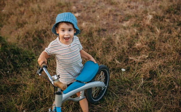 Top view of a little caucasian boy holding a bike in his hands he smiling at camera healthy lifestyl...