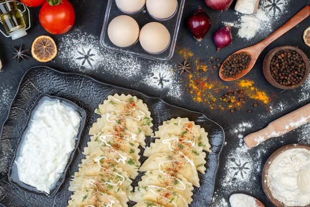 Top view little cooked dumplings with different ingredients on dark background dish dinner dough cream cooking meal