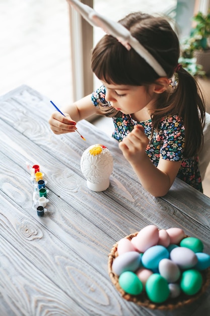 Top view little girl painting Easter egg