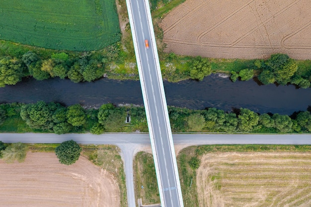 Top view of a long bridge passing through green fields