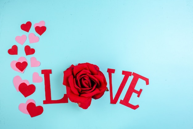 Photo top view love capital letters red and pink heart stickers on blue table with free space