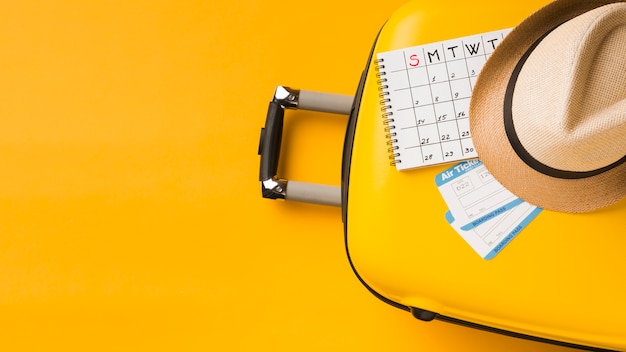 Vista dall'alto di bagagli con cappello e calendario e copia spazio