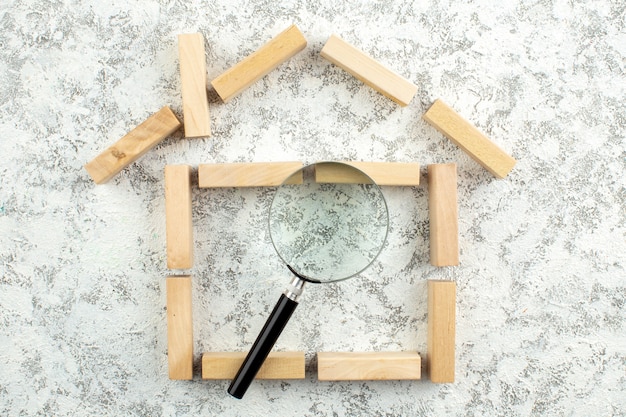 Photo top view lupa on wooden blocks house shape on grey white background