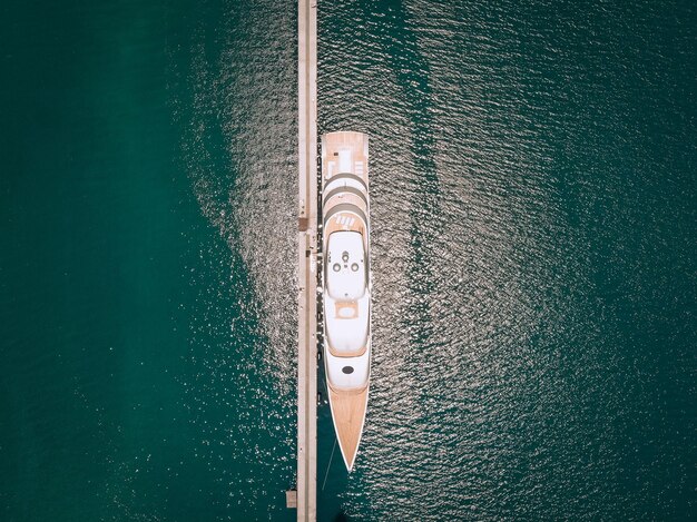 Top view of the luxurious white yachts moored at the long thin quay, blue sea in a sunny day; millionaire concept.