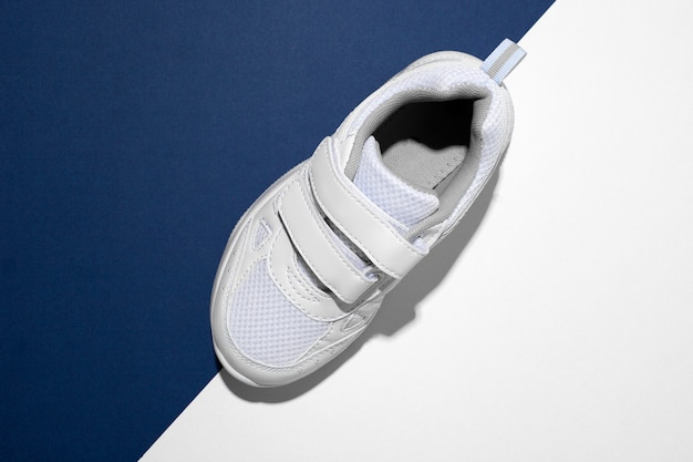 Top view macro on one white childrens running shoe with velcro fasteners for quick shoeing on a tren...