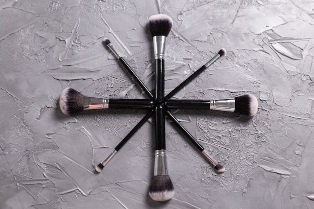 Top view of makeup brushes on grey background