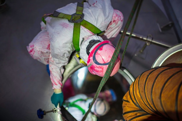 Top view male climbs up the stairs into the tank stainless chemical area confined space safety