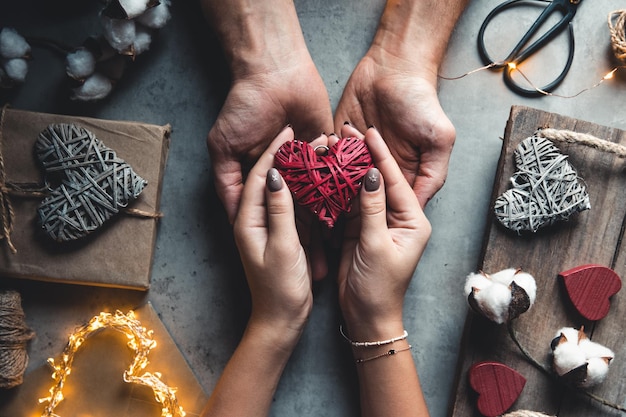 Top view of male and female hands holding red gift box Present for birthday, valentine day, Christmas, New Year.