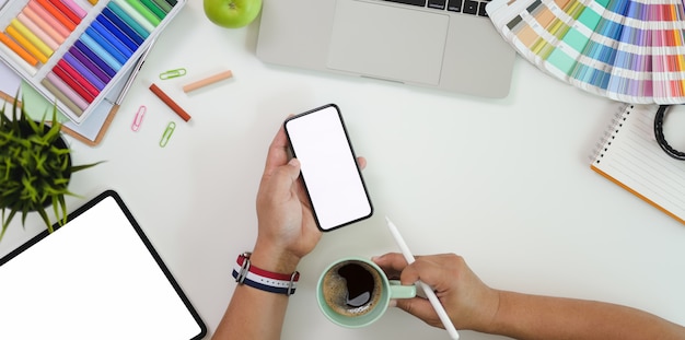 Top view of male graphic designer holding blank screen smartphone