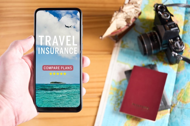 Photo top view of male hand holding mobile phone with travel insurance website on the screen