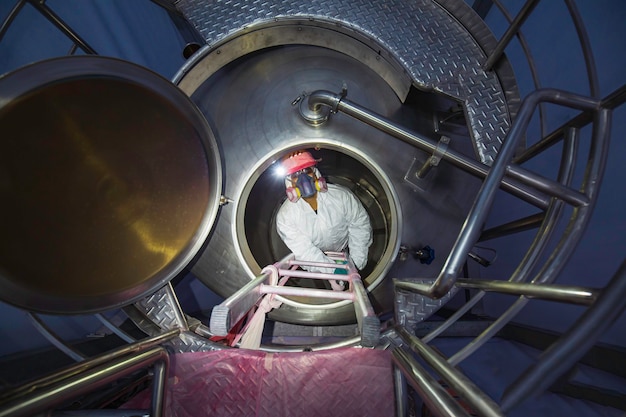 Top view male worker climb up the stairs into the tank stainless chemical area confined space safety