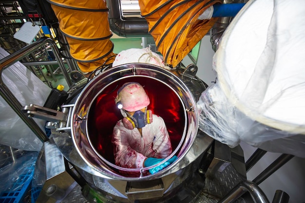 Foto il lavoratore maschio di vista superiore sale le scale nella sicurezza dello spazio confinato dell'area chimica inossidabile del serbatoio