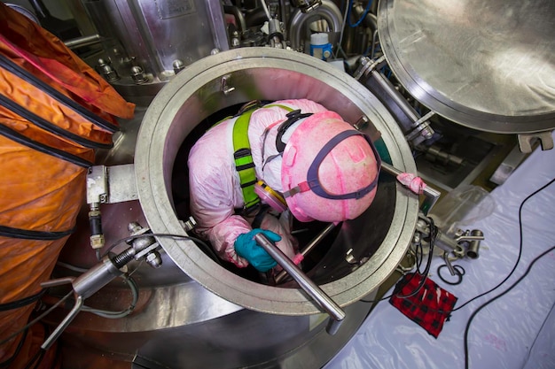 Top view male worker climb up the stairs into the tank stainless chemical area confined space