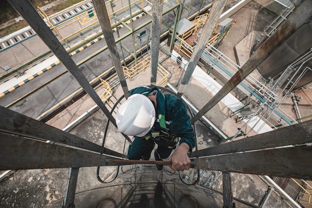 Photo top view male worker climbs up the ladder inspection stainless tank work at height