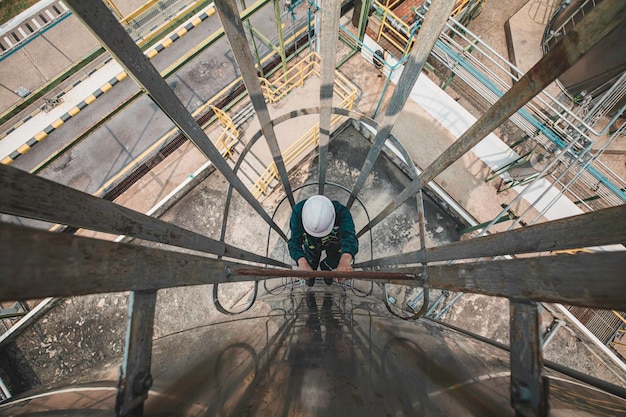 Top view male worker climbs up the ladder inspection stainless tank work at height