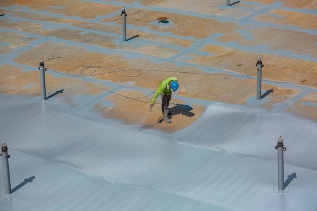 철강 산업 페인팅 및 코팅에 지붕 플레이트 탱크 표면에 사용되는 산업용 스프레이 건을 들고 상위 뷰 남성 노동자