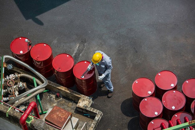 Vista dall'alto lavoratore maschio ispezione record tamburo olio stock barili rosso verticale o chimico per nell'industria.