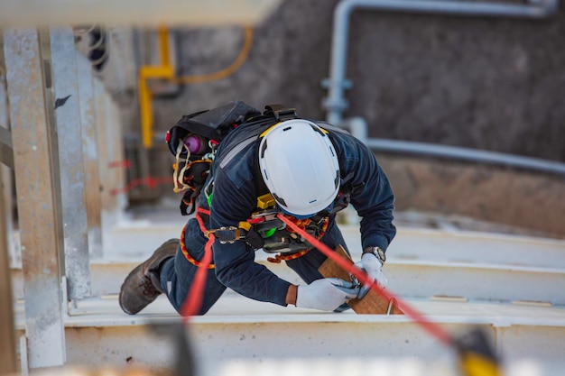 Top view male worker inspection wearing safety first harness\
rope safety line working at a high place on tank roof\
spherical