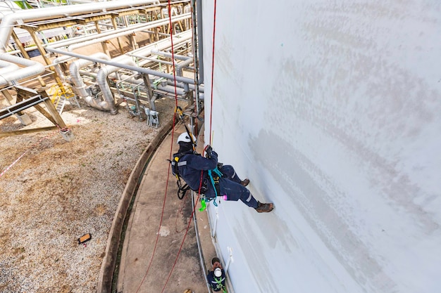 Top view male worker inspection wearing safety first harness rope safety line working at a high place on tank roof spherical