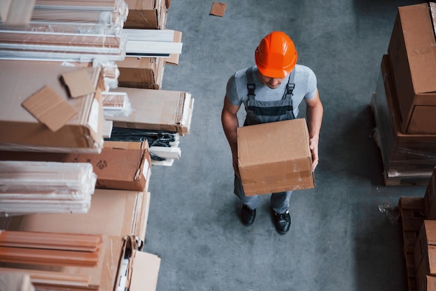 Top view of male worker in warehouse with box in hands.