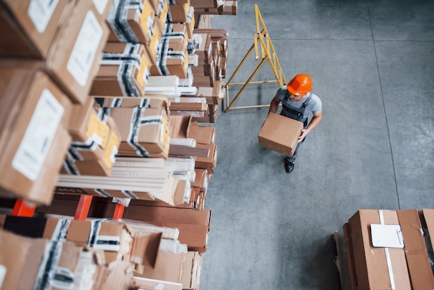 Top view of male worker in warehouse with box in hands.