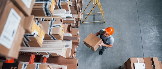 Top view of male worker in warehouse with box in hands.