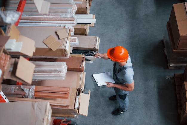 Top view of male worker in warehouse with notepad in hands.