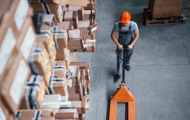 Top view of male worker in warehouse with pallet truck.