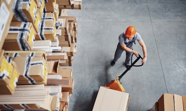 Top view of male worker in warehouse with pallet truck.