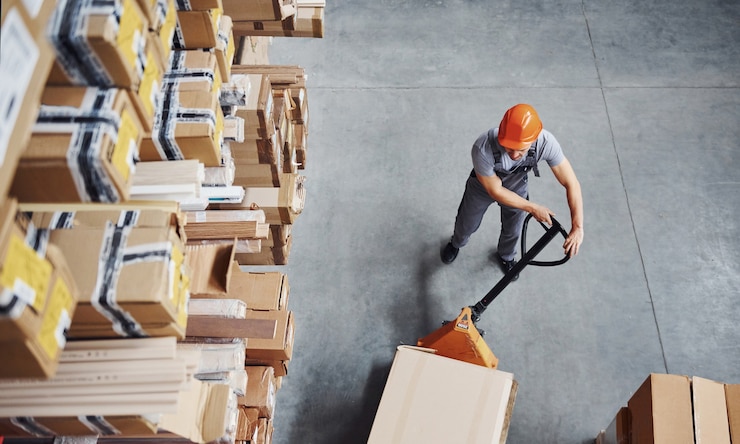 Photo top view of male worker in warehouse with pallet truck.