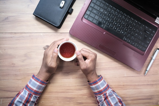 Top view of man hand holding mug on office table