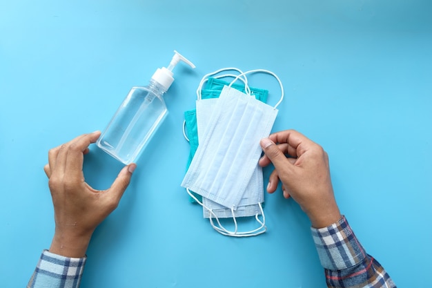 top view of man hand holding surgical face mask and sanitizer gel