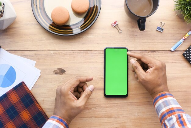 Top view of man hand using smart phone on office desk