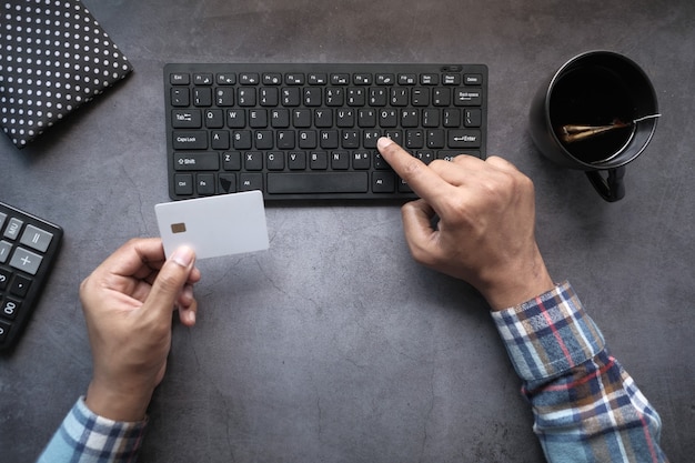 Vista dall'alto delle mani dell'uomo che tiene la carta di credito e digitando sulla tastiera