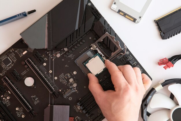 Top view of man hands puts cpu on motherboard, computer parts, Electronics repair and upgrade copy space. Motherboard, processor cpu, cooler, radiator, flat lay.