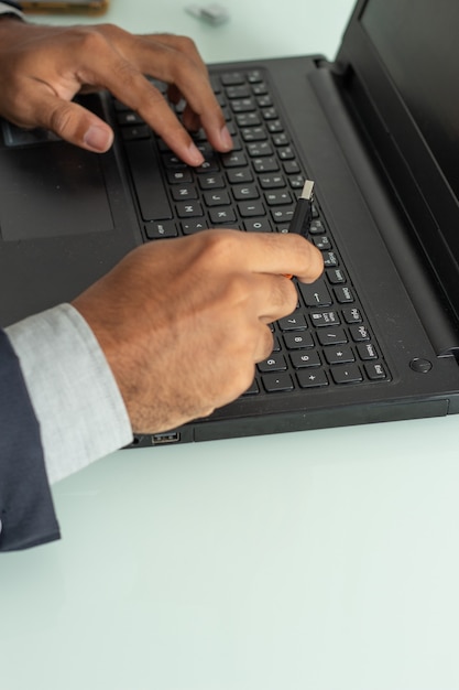 Top view of a man holding on  a pen drive under the computer