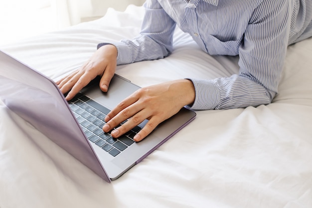 Top view man lying on stomach using laptop on bed