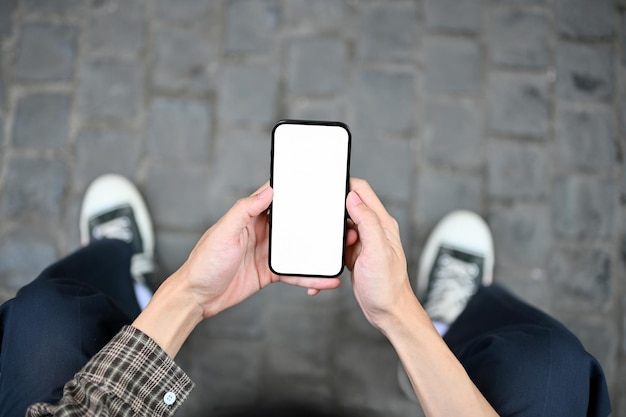 Top view of a man sits on the street and uses his smartphone chat text application social media