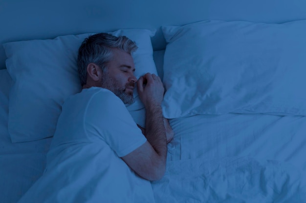 Top view of man sleeping alone in bed at night