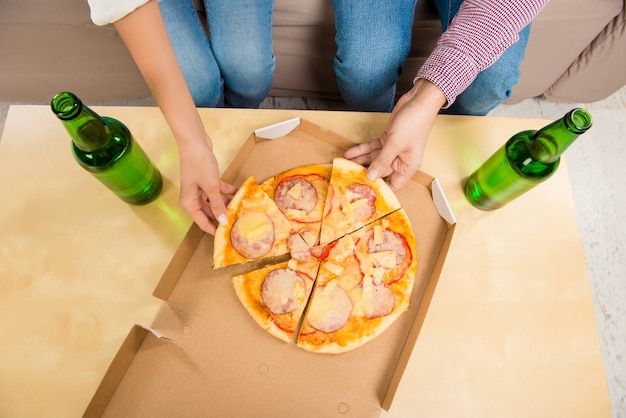 Top view of man and woman eating pizza with beer