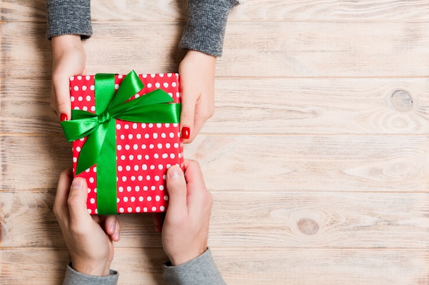 Top view of a man and a woman holding a gift on wooden.